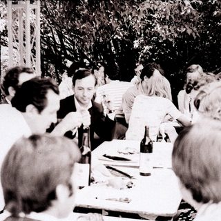 Group gathered around a table at an outdoor social event.