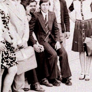 Group of people posing outside a building in formal 1960s attire.