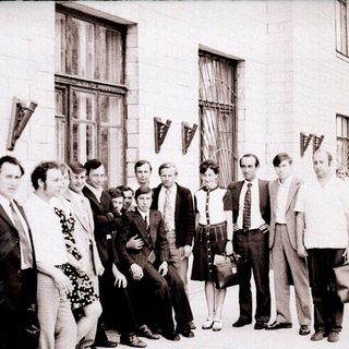 Group of people posing outside an industrial building.