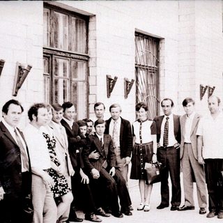 Group of people posing outside an industrial building.