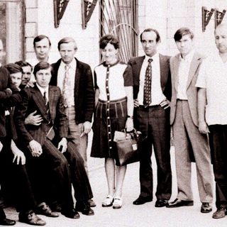 Group of people posing outside an industrial building.