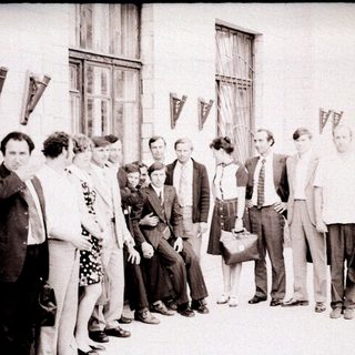 Group of people standing outside a building in the 1970s-80s.
