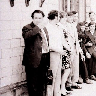 Group of people standing outside a building in the 1970s-80s.