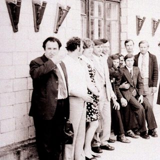 Group of people standing outside a building in the 1970s-80s.