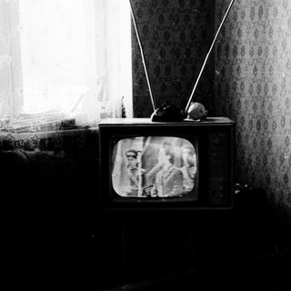Vintage room with old CRT TV displaying grainy image.