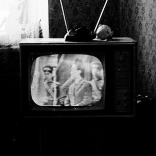 Vintage room with old CRT TV displaying grainy image.