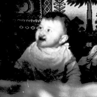 Baby in cozy indoor setting with decorative wall.