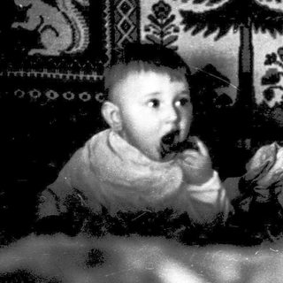 Toddler eating with traditional embroidered wall backdrop.