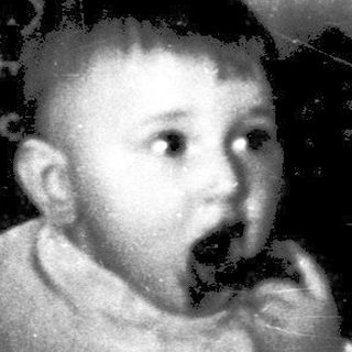 Toddler eating with traditional embroidered wall backdrop.