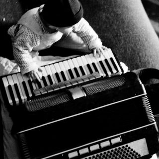 Person playing vintage accordion on couch.