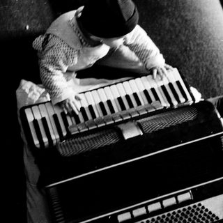 Person playing vintage accordion on couch.