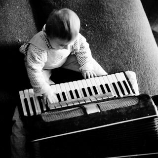Young child playing accordion indoors.