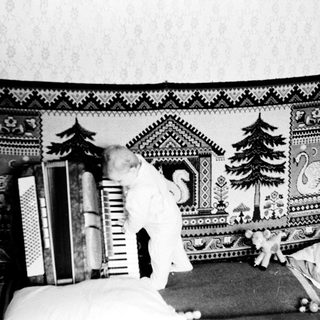 Child playing on bed with patterned blanket and books.