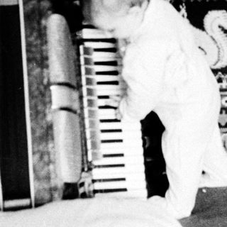 Child playing on bed with patterned blanket and books.