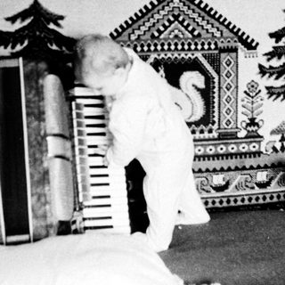 Child playing on bed with patterned blanket and books.
