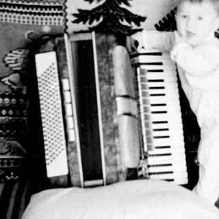 Baby standing on bed near ladder and books.