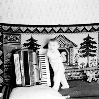 Baby standing on bed near ladder and books.