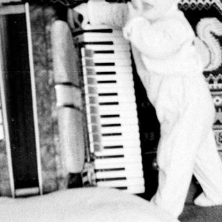 Baby standing on bed near ladder and books.