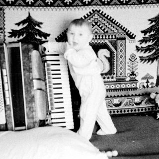 Baby standing on bed near ladder and books.