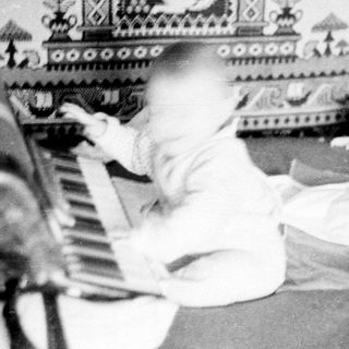 Child playing piano in decorated room with nature motifs.