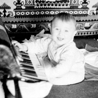 Baby playing with toy piano indoors.