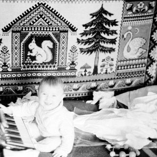 Baby sitting on piano in decorated nursery.