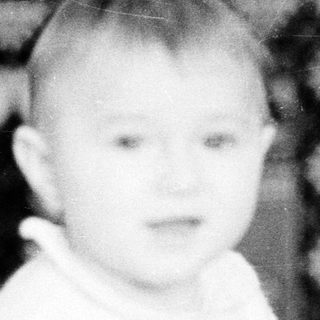 Young child indoors near decorative wall tapestry.
