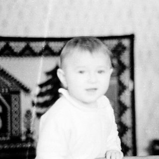 Young child indoors near decorative wall tapestry.