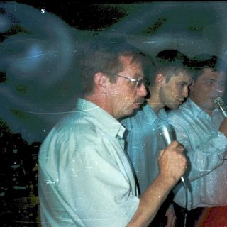 Two men speaking into microphones at an event.