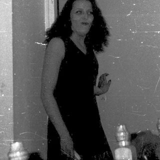 Woman standing in doorway holding small object.