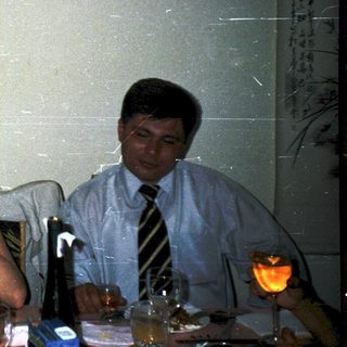 Three people at a celebratory table, one toasting another.