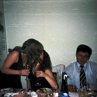 Three people at a celebratory table, one toasting another.
