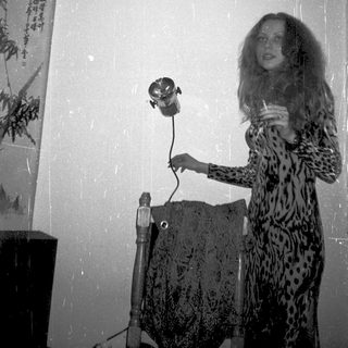 Woman in leopard print dress using vintage camera indoors.