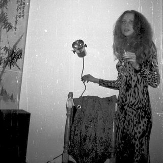 Woman in leopard print dress using vintage camera indoors.