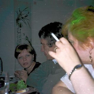 Three people dining indoors, focused on meal.