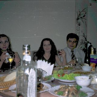 Three people dining together at a table with food and drinks.