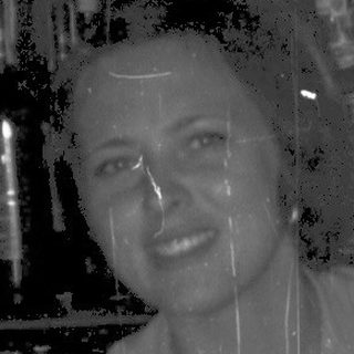 Barista smiling while holding two drinks behind a bar.