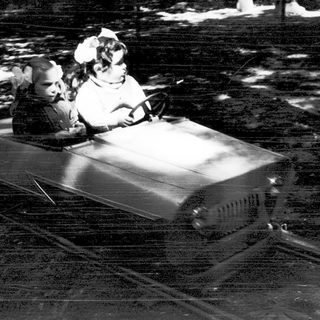 Two children riding a dark indoor log flume ride.