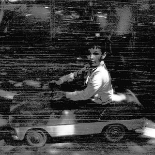 A person driving a vintage car at night.