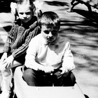 Two children playing with toy cars outdoors.