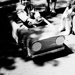 Two children playing with toy cars outdoors.