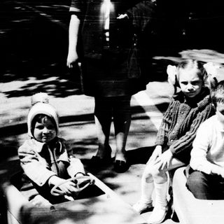 Two children playing with toy cars outdoors.