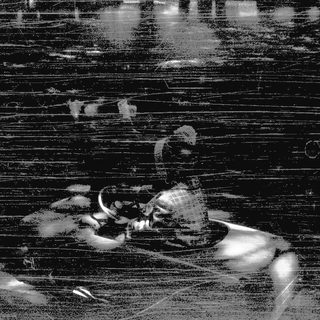 Blurred figure sitting on wooden bench at night.