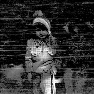 Child sitting alone against a dark wall.