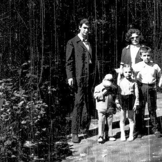 Family posing outdoors in a rain-soaked forest.