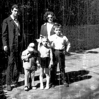 Family posing outdoors in a rain-soaked forest.