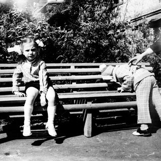 Two children playing on a bench outdoors.