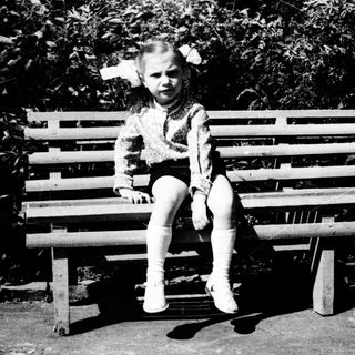 Two children playing on a bench outdoors.