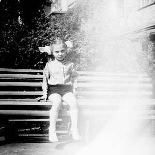 Child sitting on bench in sunlight.