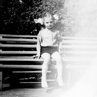 Child sitting on bench in sunlight.